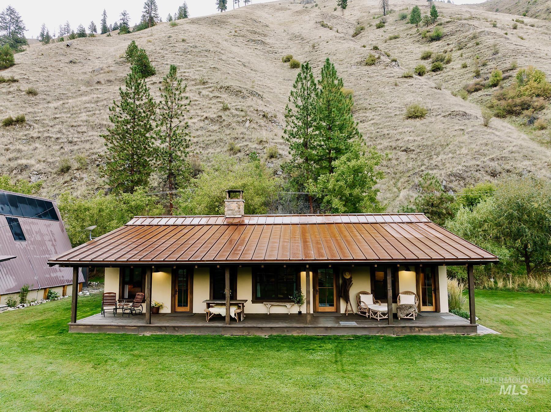 Back of property featuring a standing seam roof, a metal roof, a chimney, a yard, and a porch