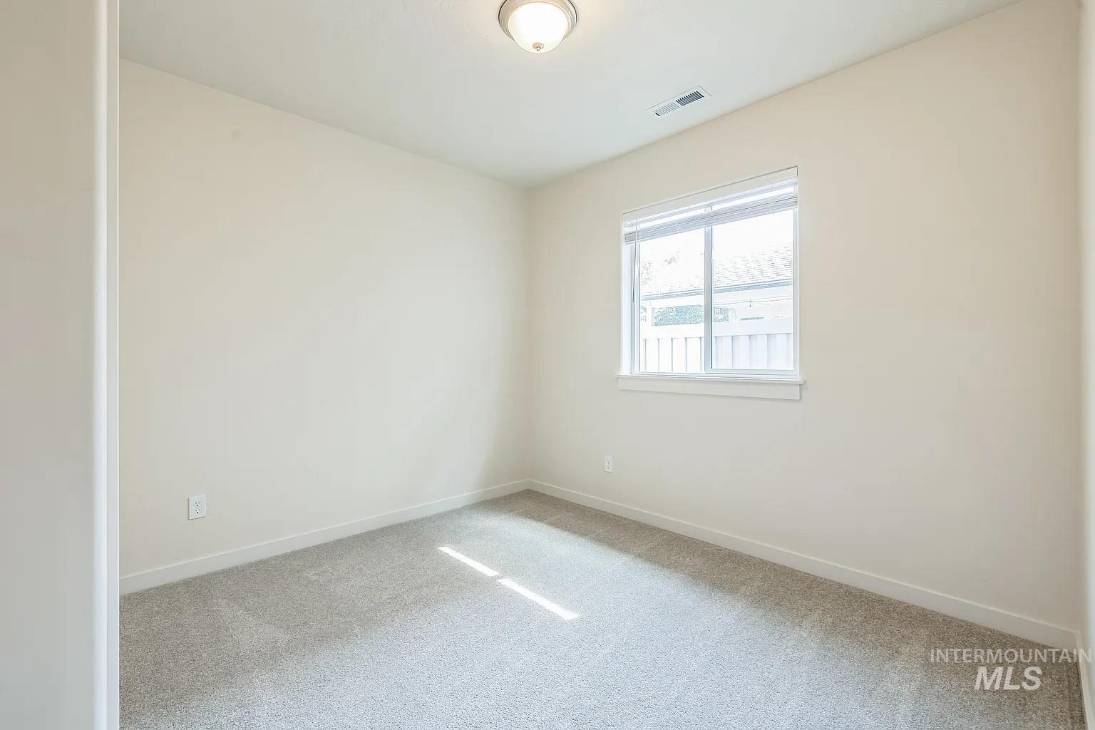 Bright room featuring neutral-toned walls, light gray carpet, and a white-framed window