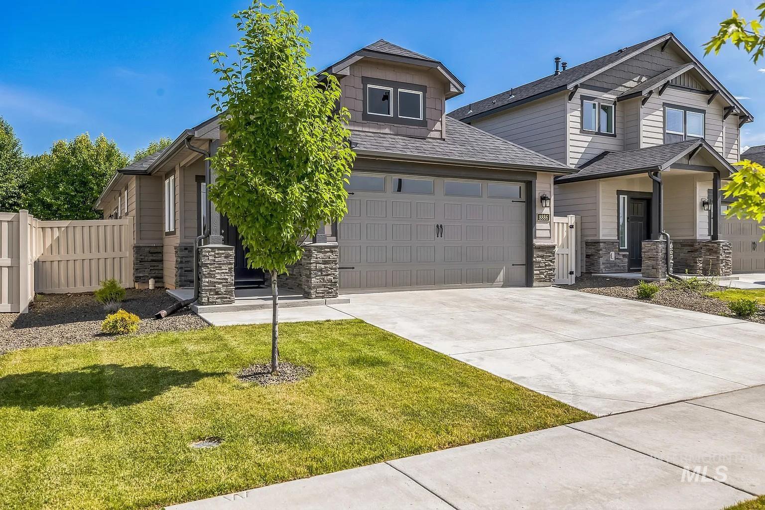 Contemporary exterior with stone accents, an attached two-car garage, concrete driveway, and established front landscaping
