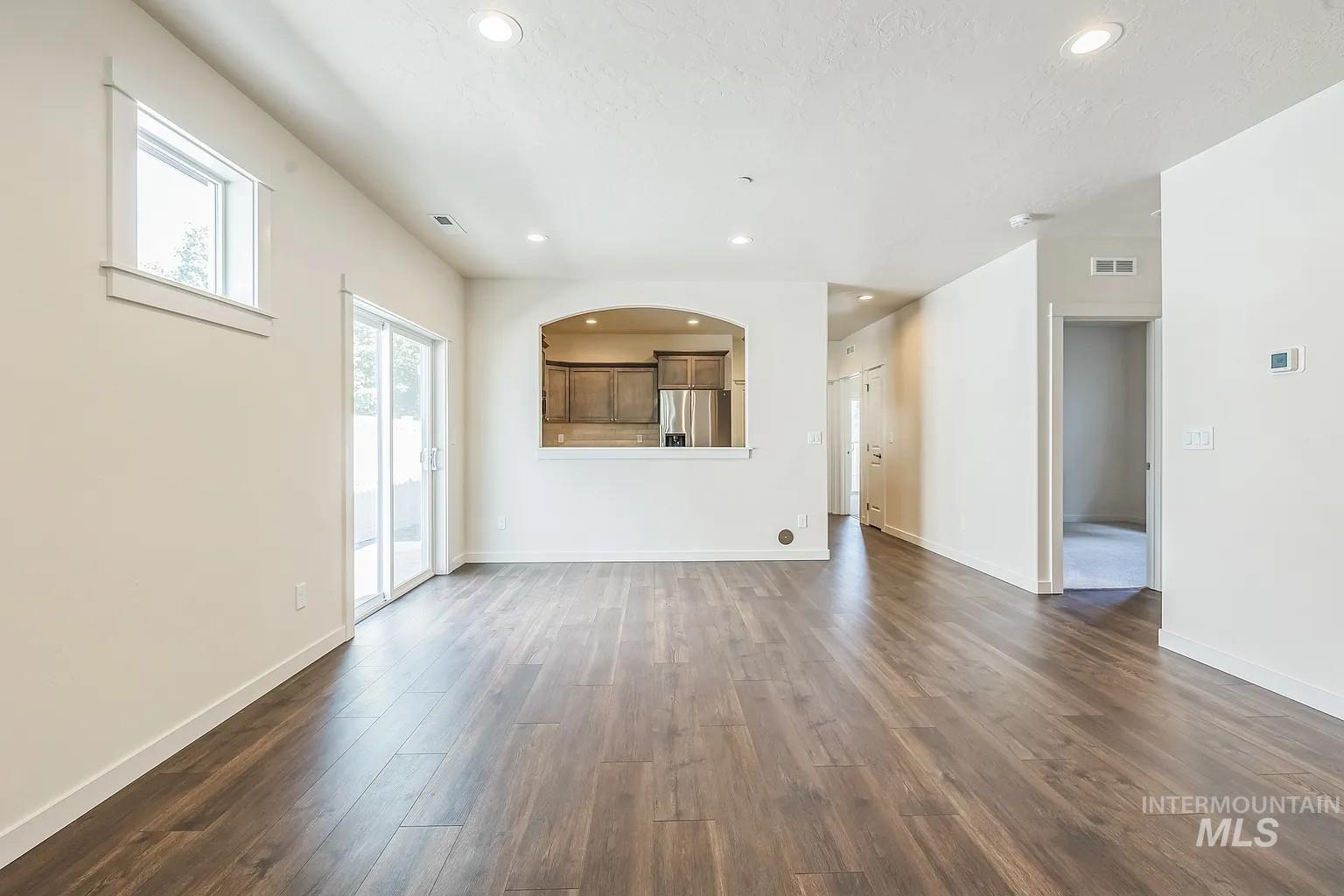 Spacious living area featuring wood-finish flooring, recessed lighting, and a sliding glass door for outdoor access