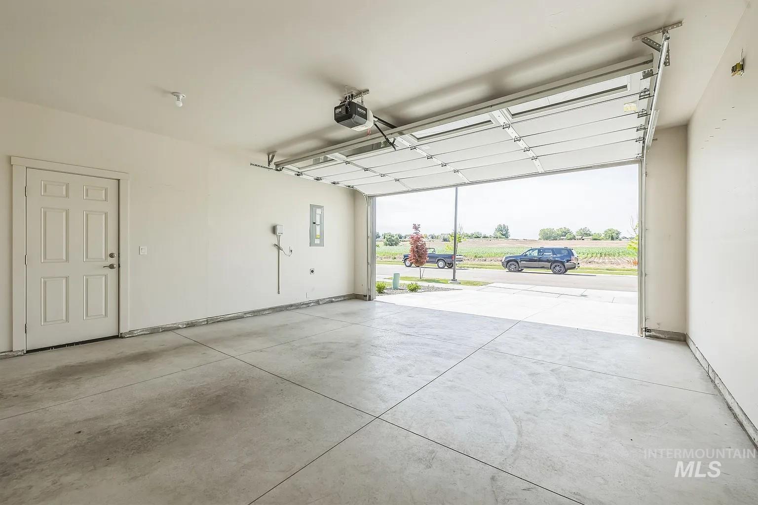 Spacious two-car garage featuring a concrete floor, an interior access door, and an automatic garage door opener