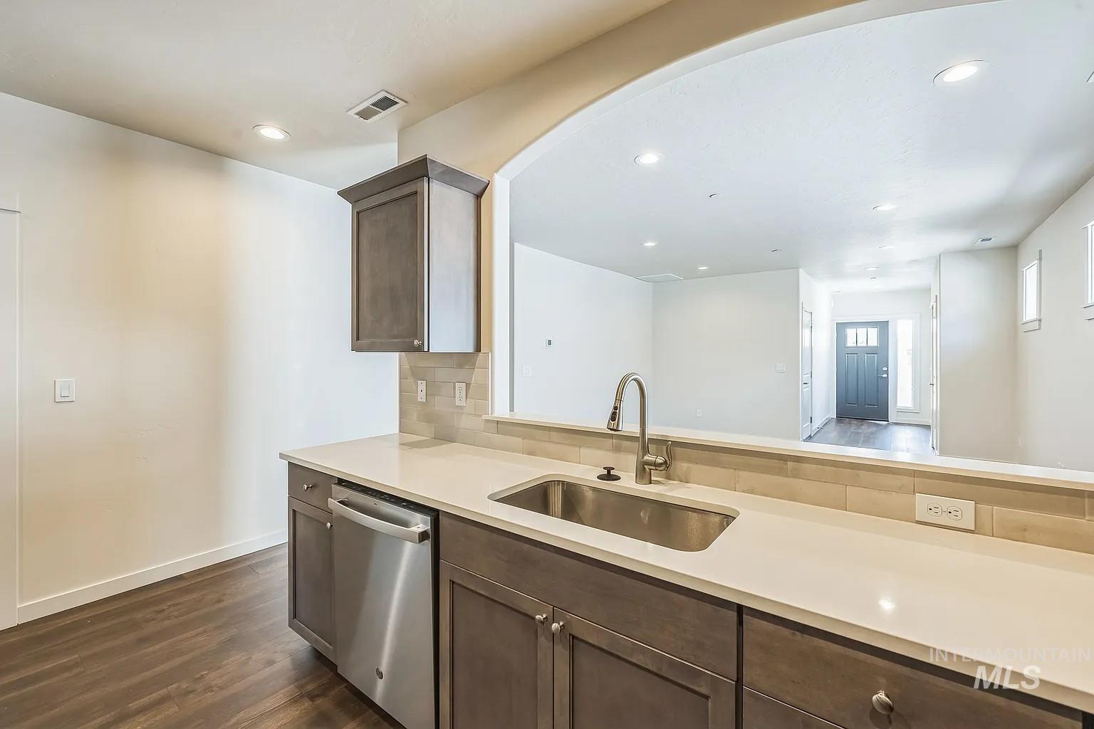 Kitchen featuring stainless steel appliances, a single basin sink with a high-arch faucet, light-toned countertops, and a subway tile backsplash