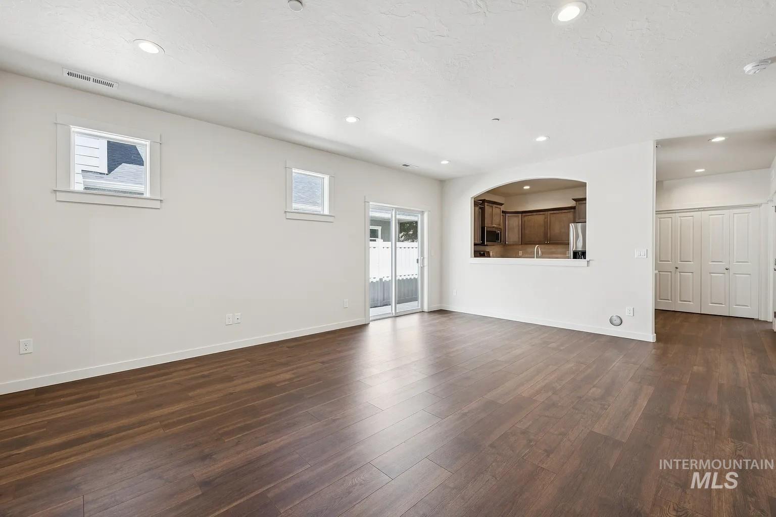 Open-concept living space featuring wood-finish flooring, recessed lighting, and a sliding glass door to the exterior