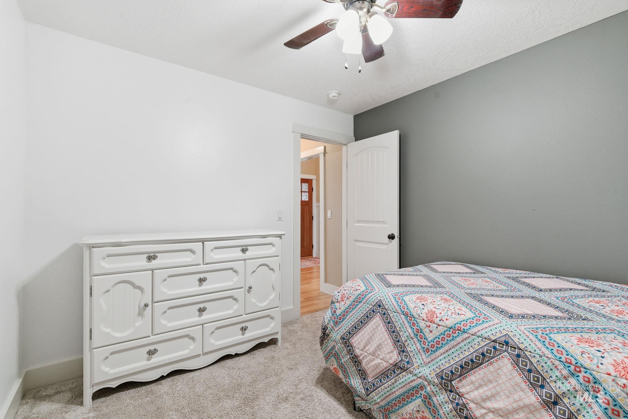 Bedroom with light colored carpet, ceiling fan, and a textured ceiling