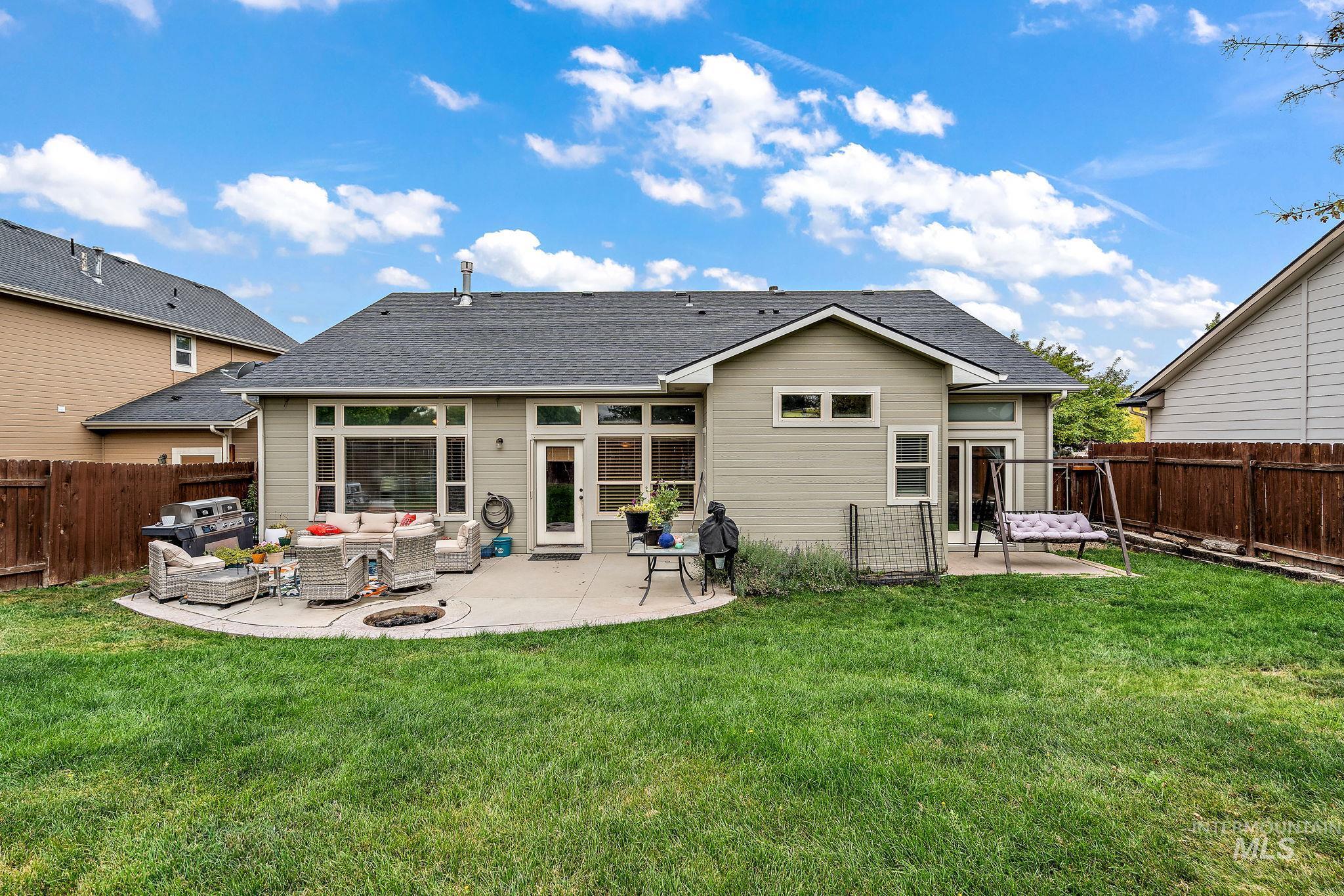 Back of house with an outdoor living space with a fire pit, a fenced backyard, a patio area, and a shingled roof
