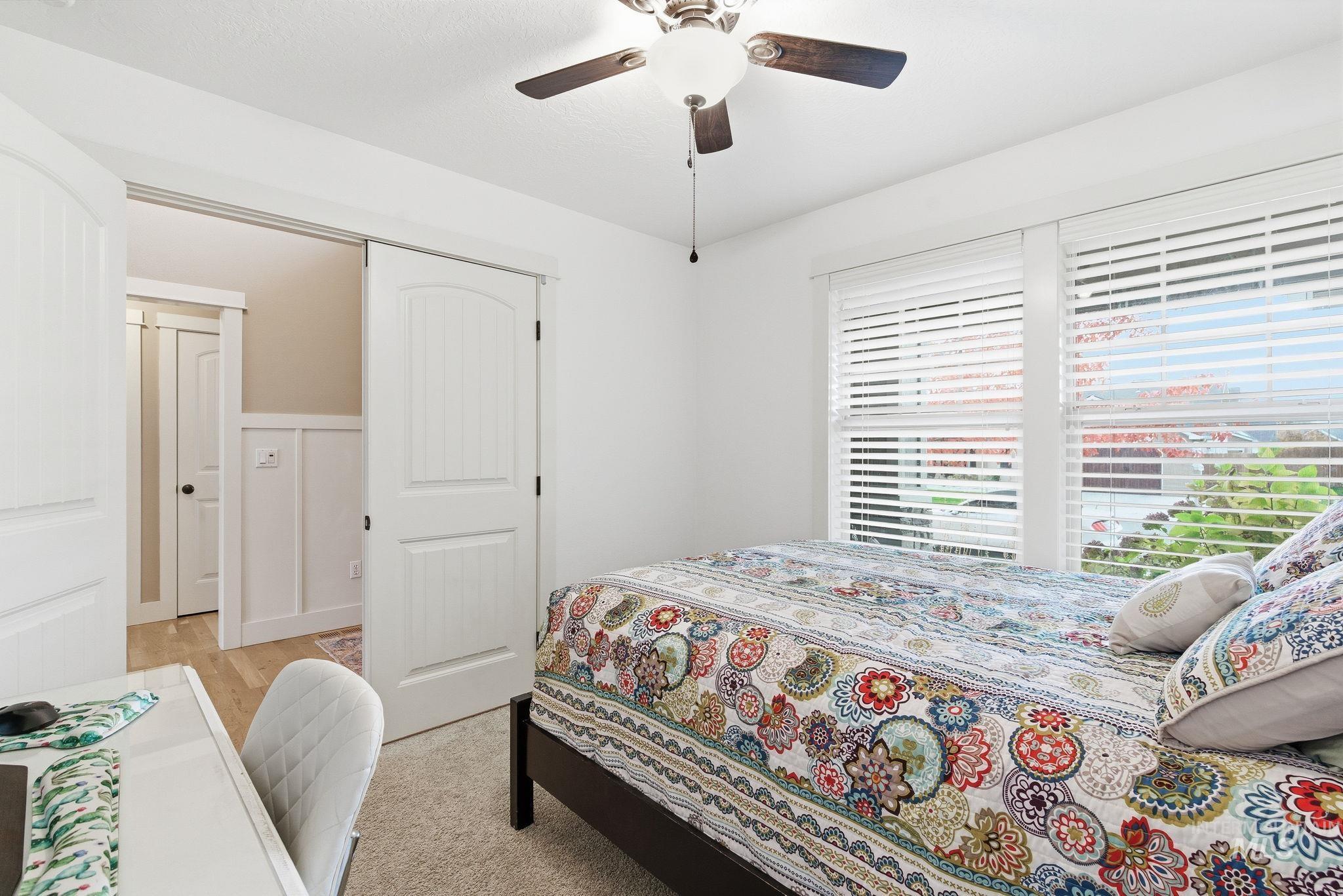 Bedroom with ceiling fan, a closet, and light carpet