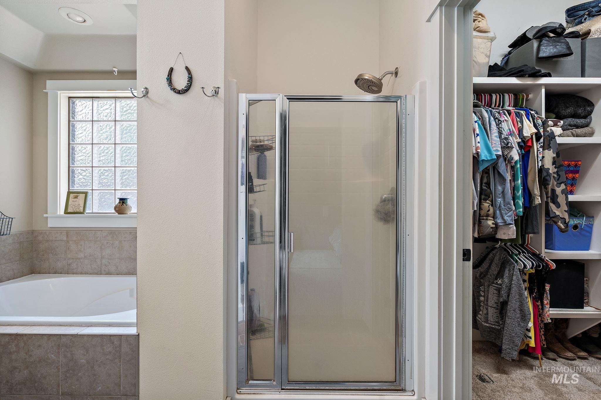 Full bath featuring a stall shower, a garden tub, and a spacious closet