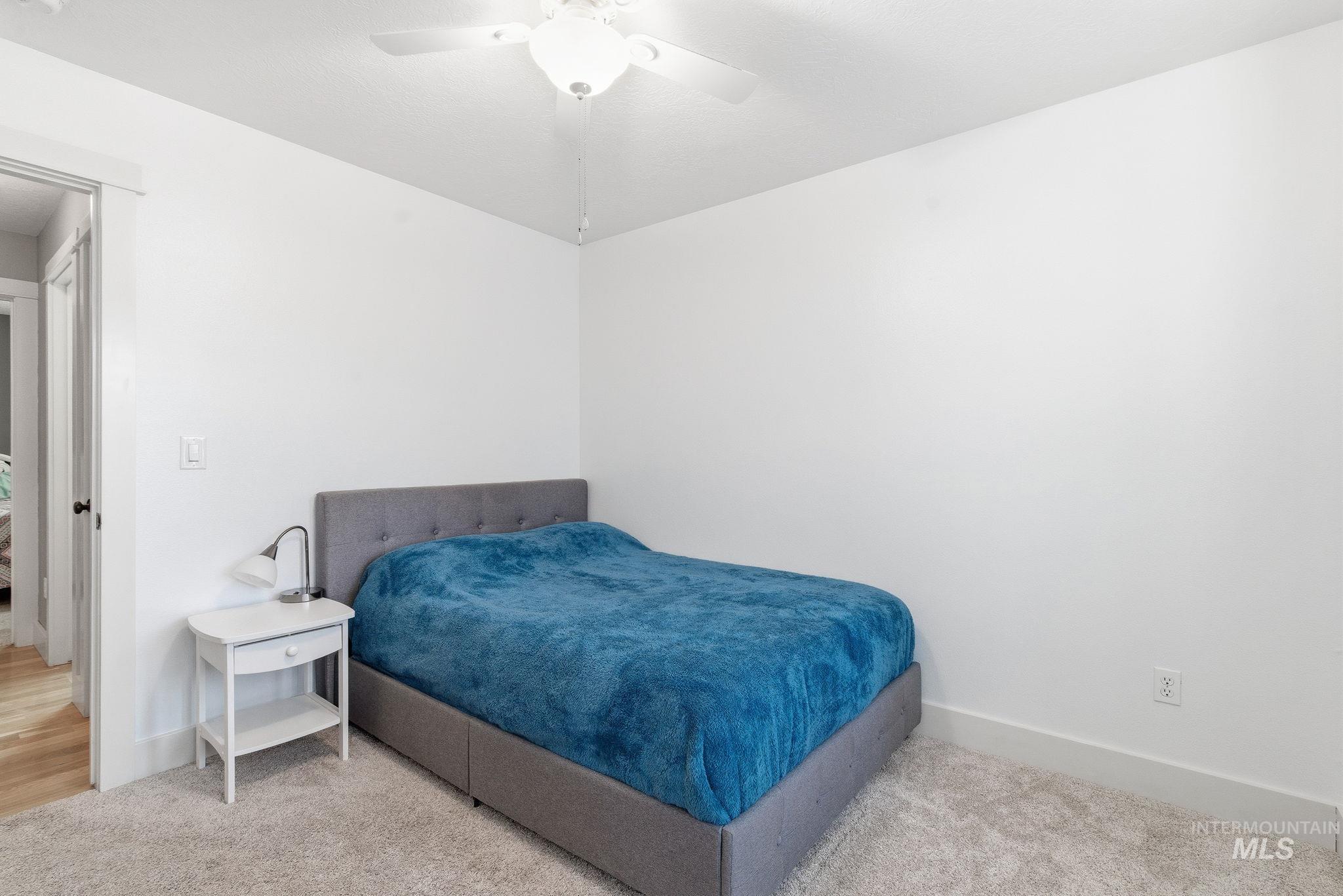 Carpeted bedroom with ceiling fan and baseboards