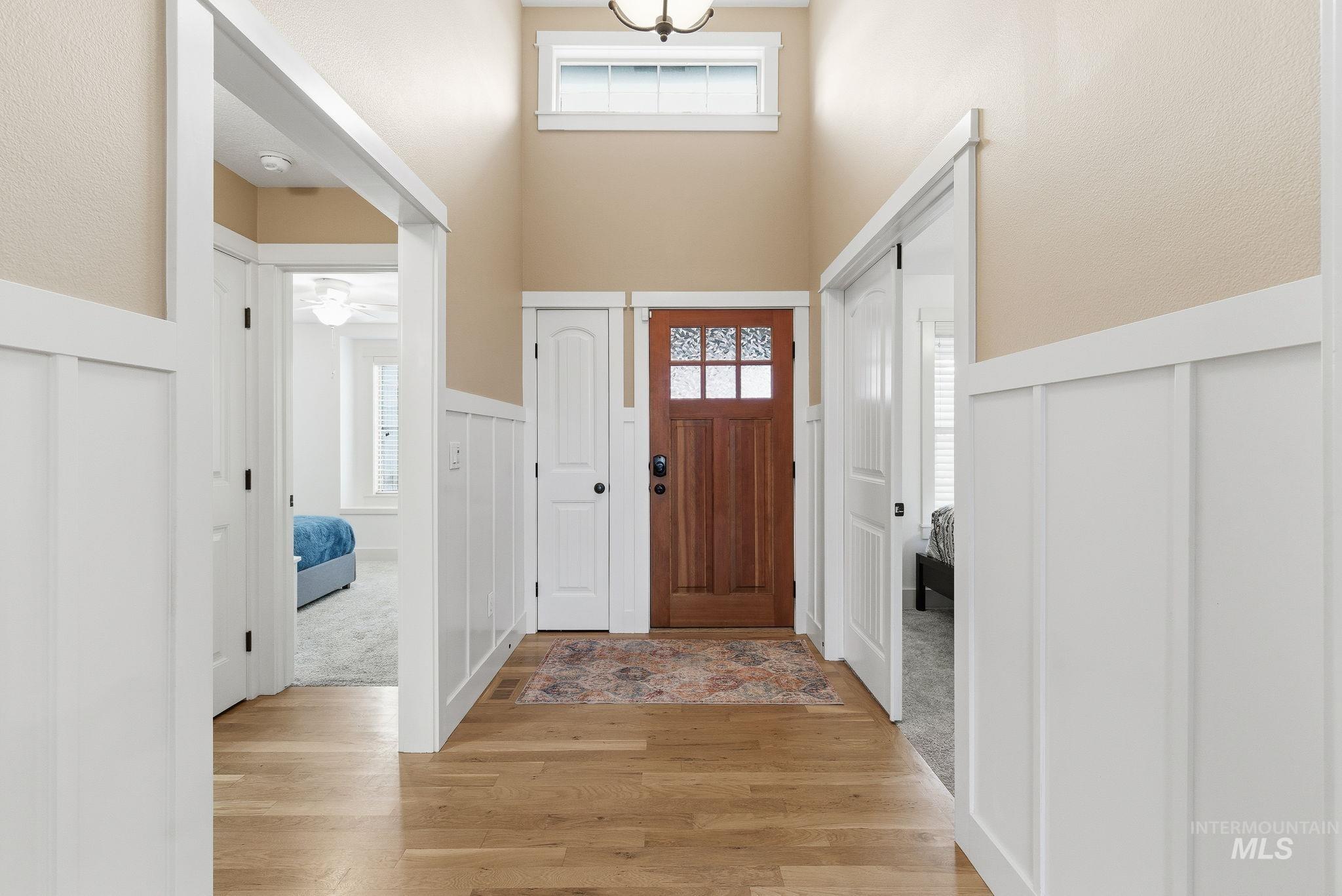 Foyer featuring wainscoting, light wood-type flooring, a decorative wall, and ceiling fan