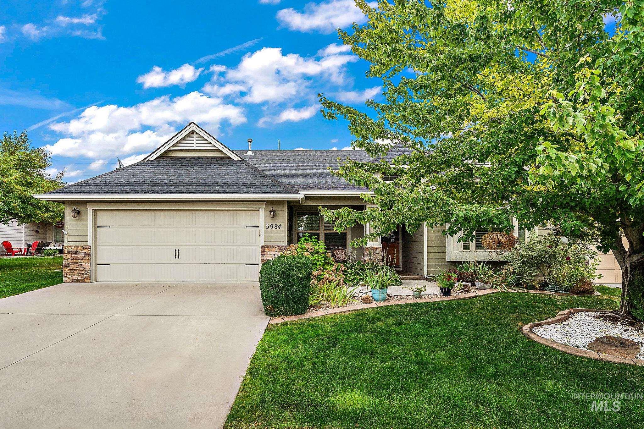 Single story home with roof with shingles, stone siding, a front lawn, and driveway