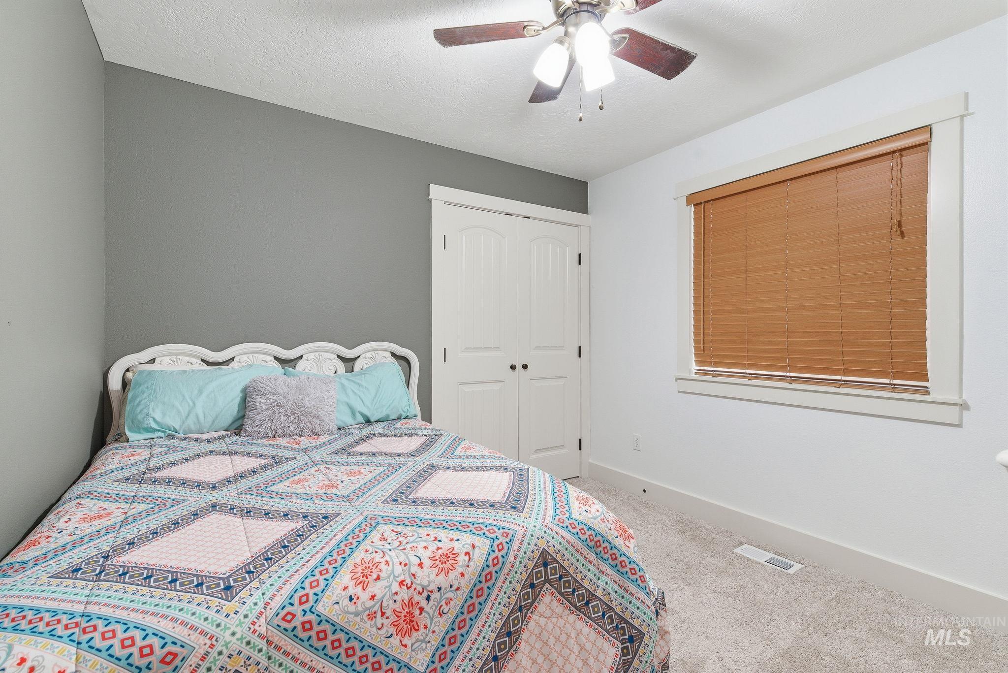 Carpeted bedroom with a ceiling fan, a closet, and a textured ceiling