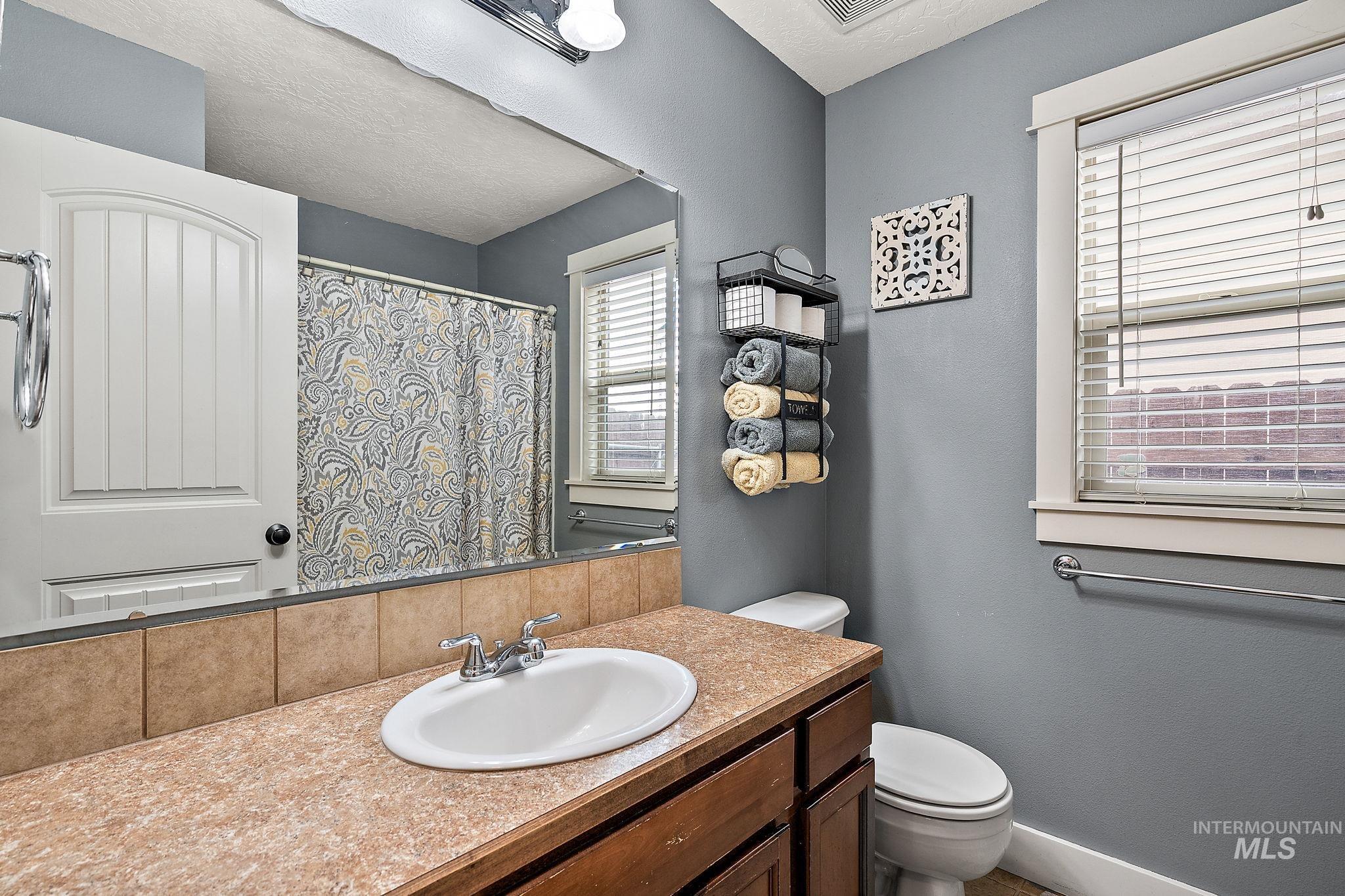 Bathroom featuring vanity, a textured wall, and curtained shower