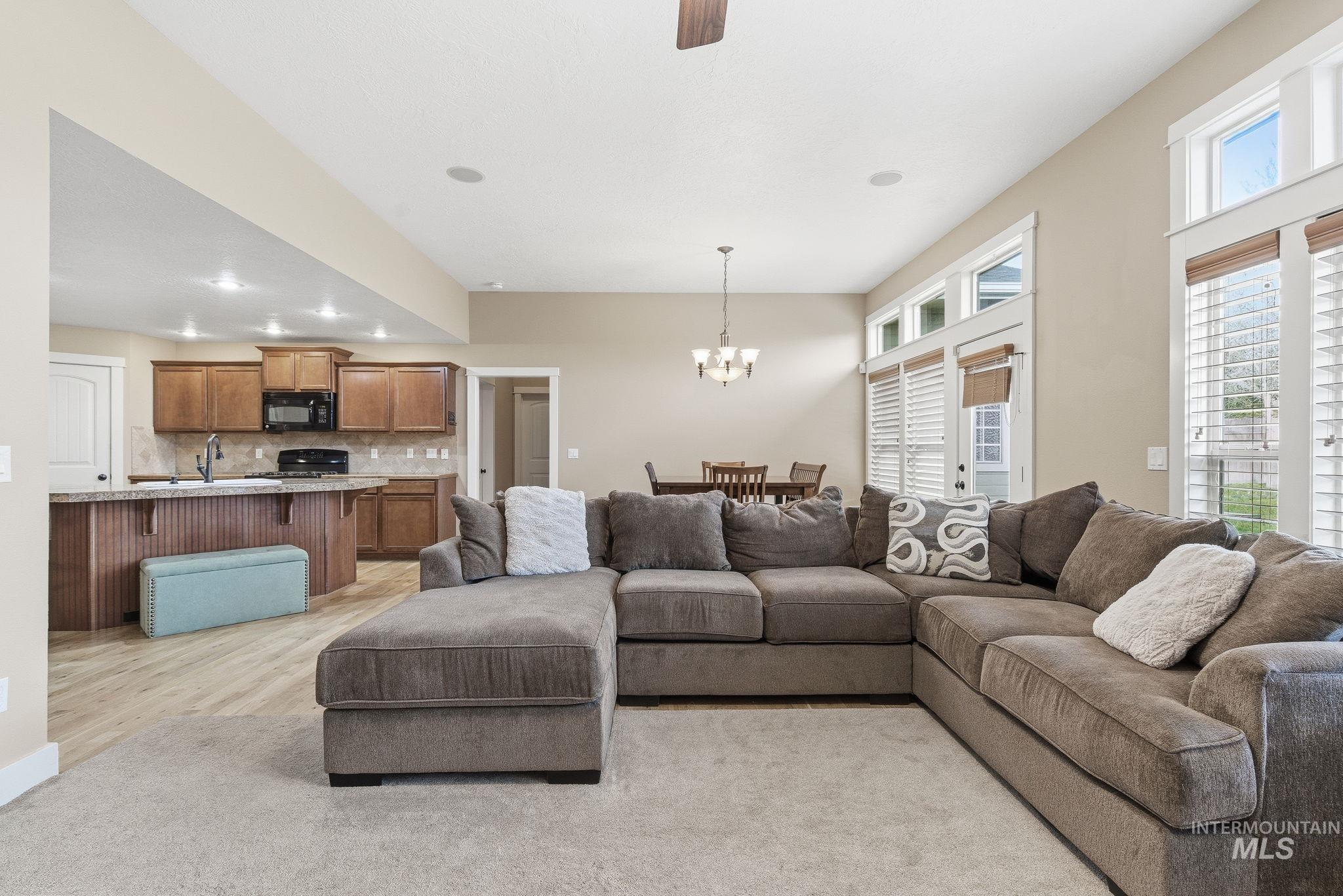 Living area featuring ceiling fan, light wood-type flooring, a chandelier, and recessed lighting