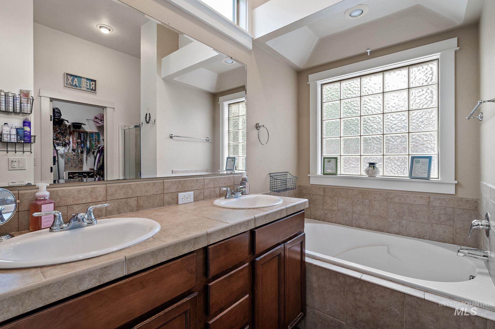Bathroom with a bath, double vanity, and a shower stall