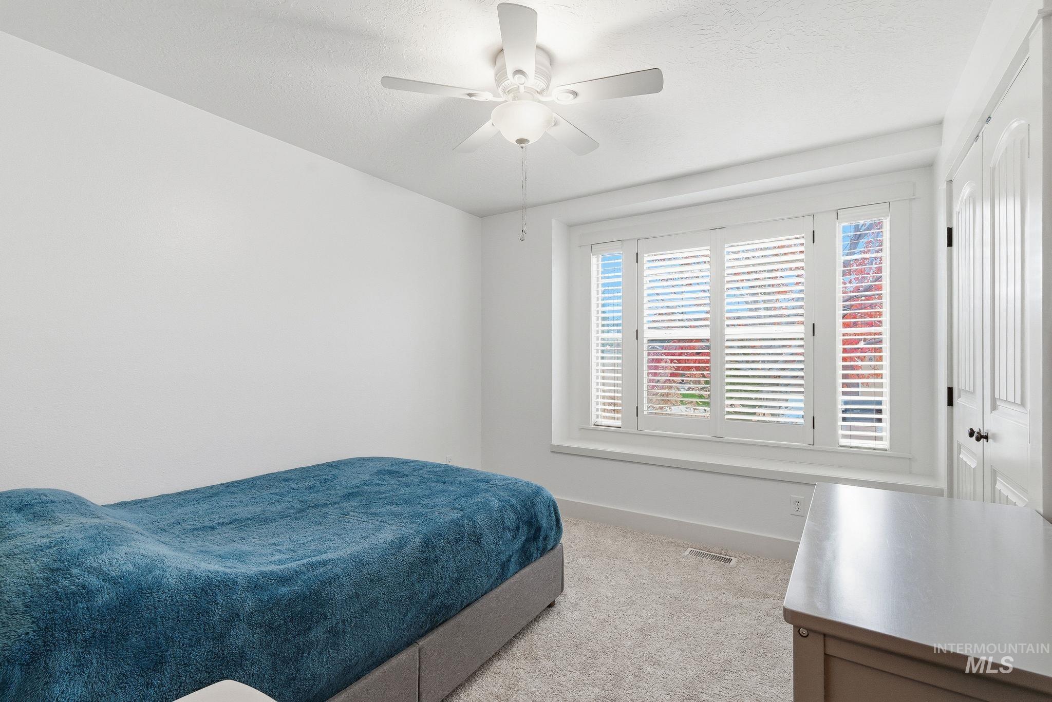 Bedroom featuring light carpet, a ceiling fan, a closet, and a textured ceiling