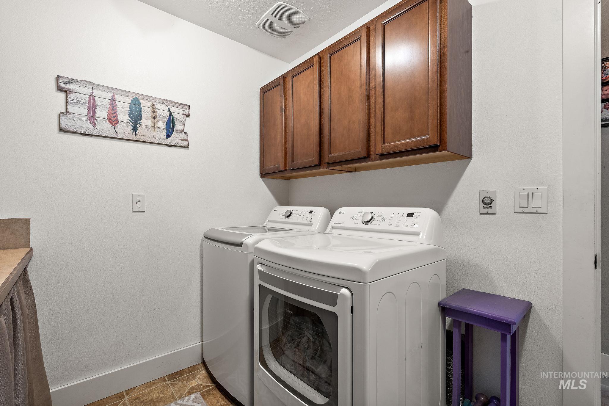 Laundry area featuring cabinet space, washing machine and dryer, and light tile patterned floors