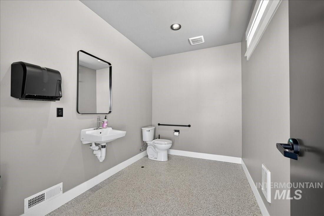 Bathroom featuring speckled floor and toilet