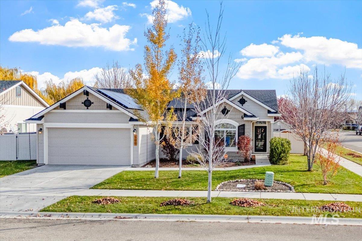 View of front of house featuring driveway, roof mounted solar panels, and an attached garage