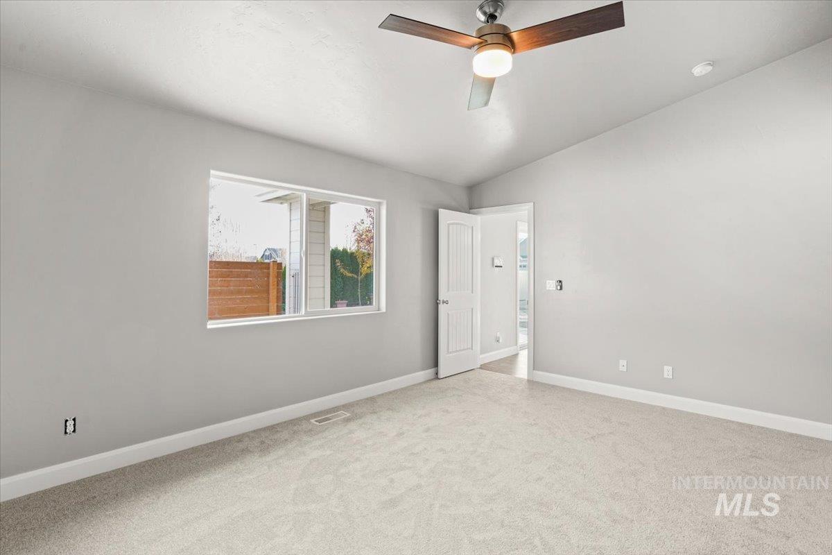 Empty room with lofted ceiling, carpet, and a ceiling fan