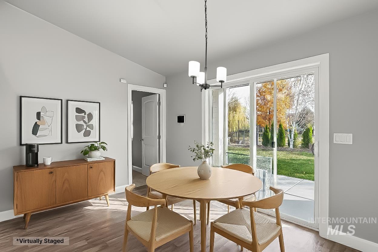Dining area with wood finished floors, lofted ceiling, and a chandelier