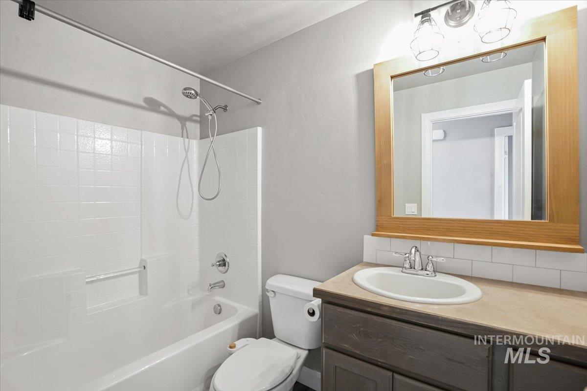 Bathroom with shower / bath combination, vanity, and tasteful backsplash
