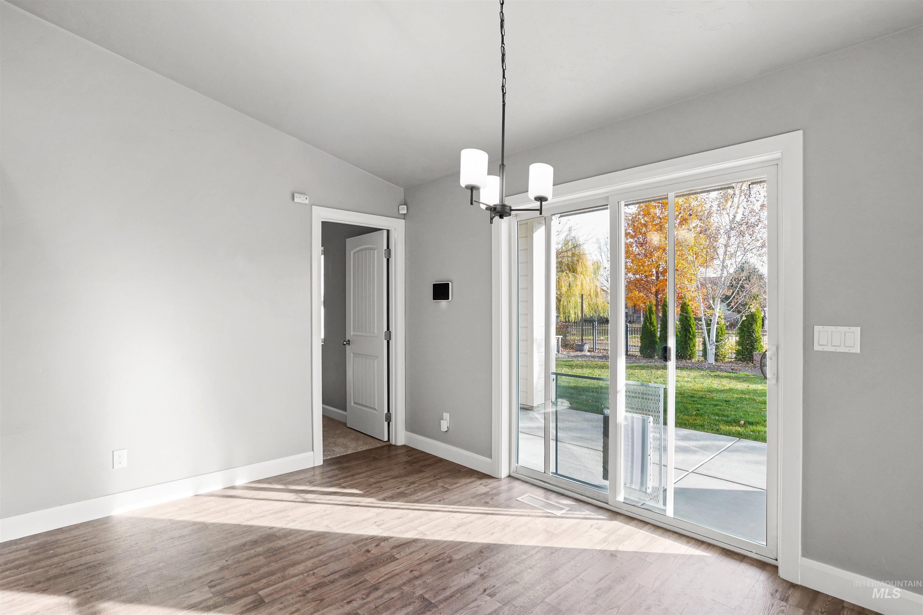 Unfurnished dining area featuring a chandelier, light wood-style floors, and vaulted ceiling