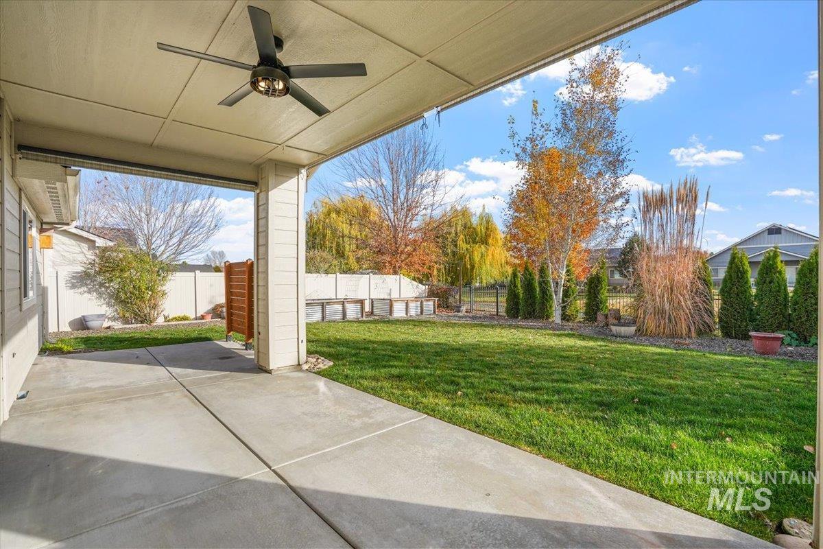 Fenced backyard featuring ceiling fan and a patio