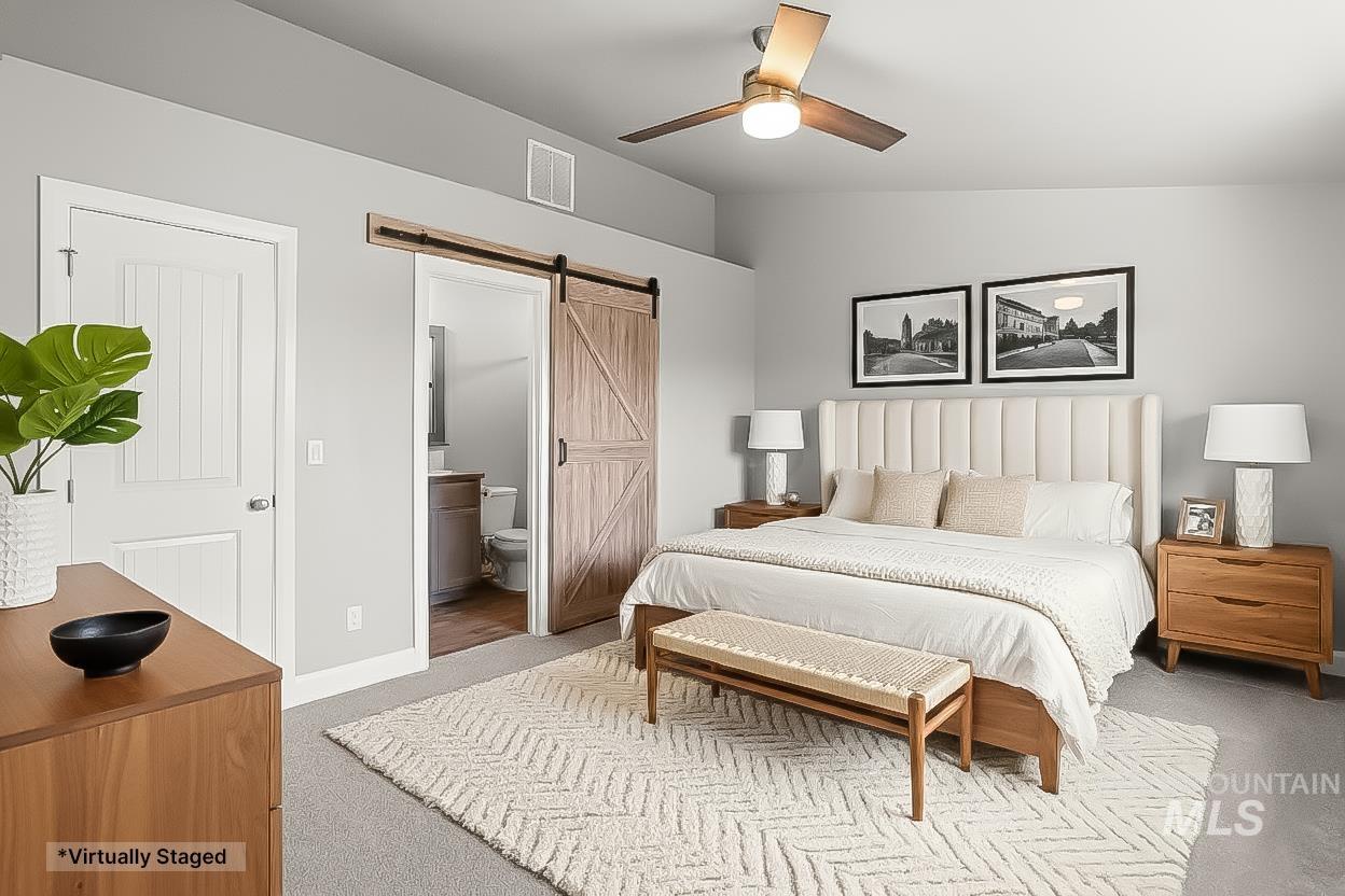 Bedroom featuring a barn door, carpet floors, connected bathroom, vaulted ceiling, and ceiling fan