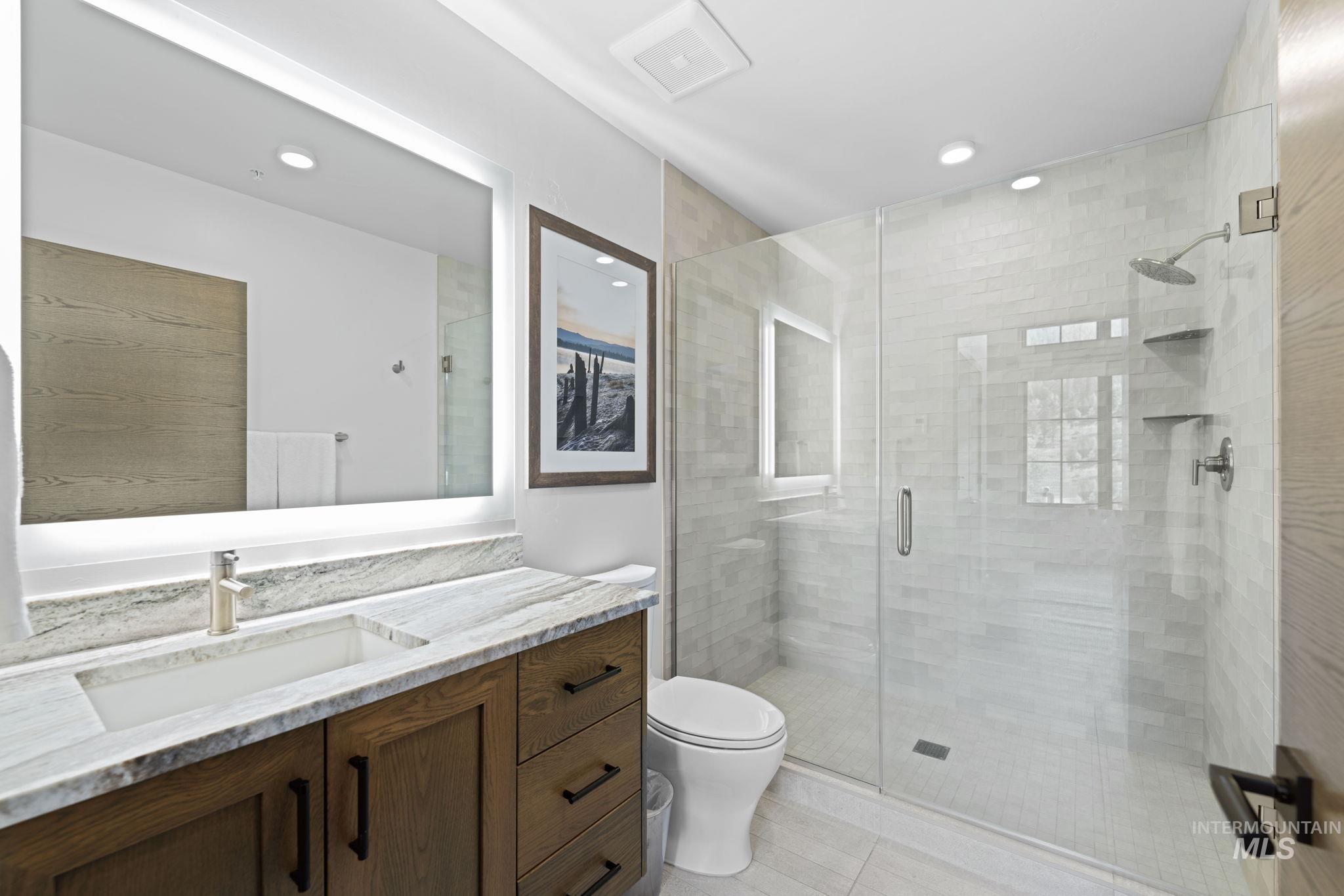 Bathroom with vanity, a shower stall, and recessed lighting