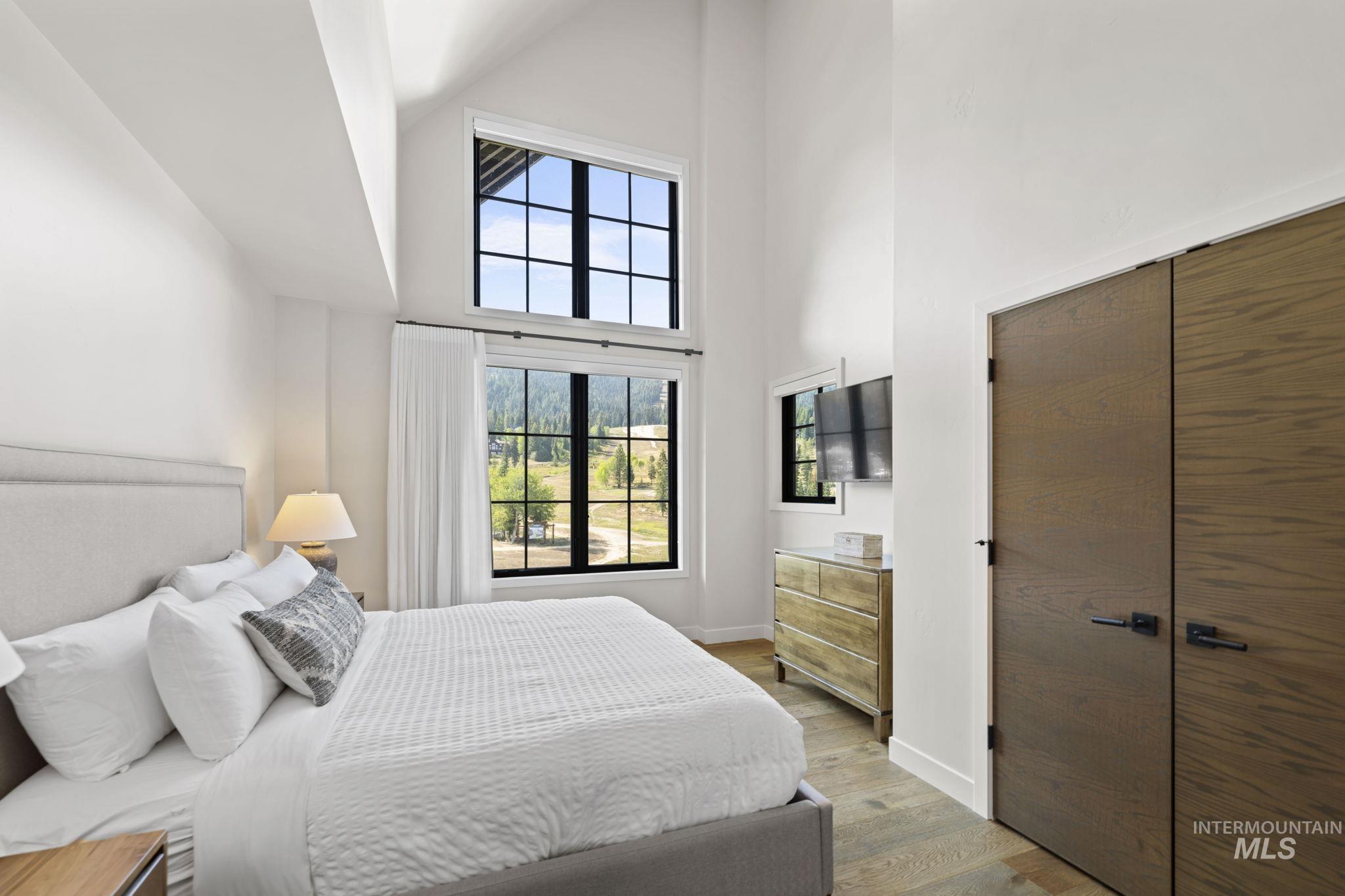 Bedroom with a towering ceiling, light wood-style flooring, and a closet