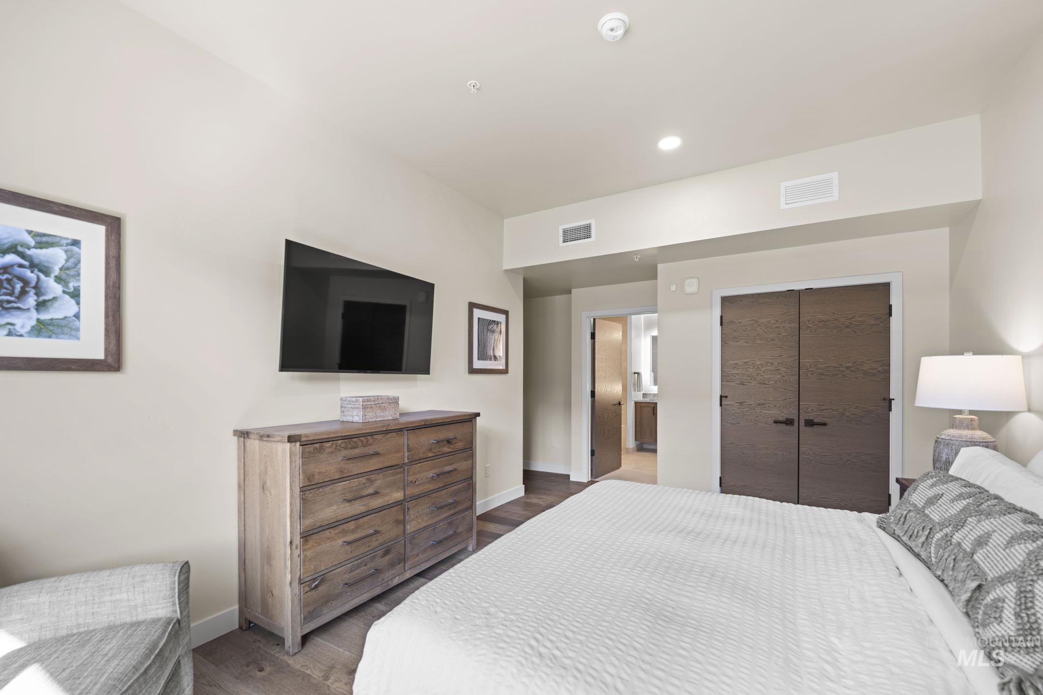 Bedroom with dark wood finished floors, recessed lighting, a closet, and ensuite bathroom