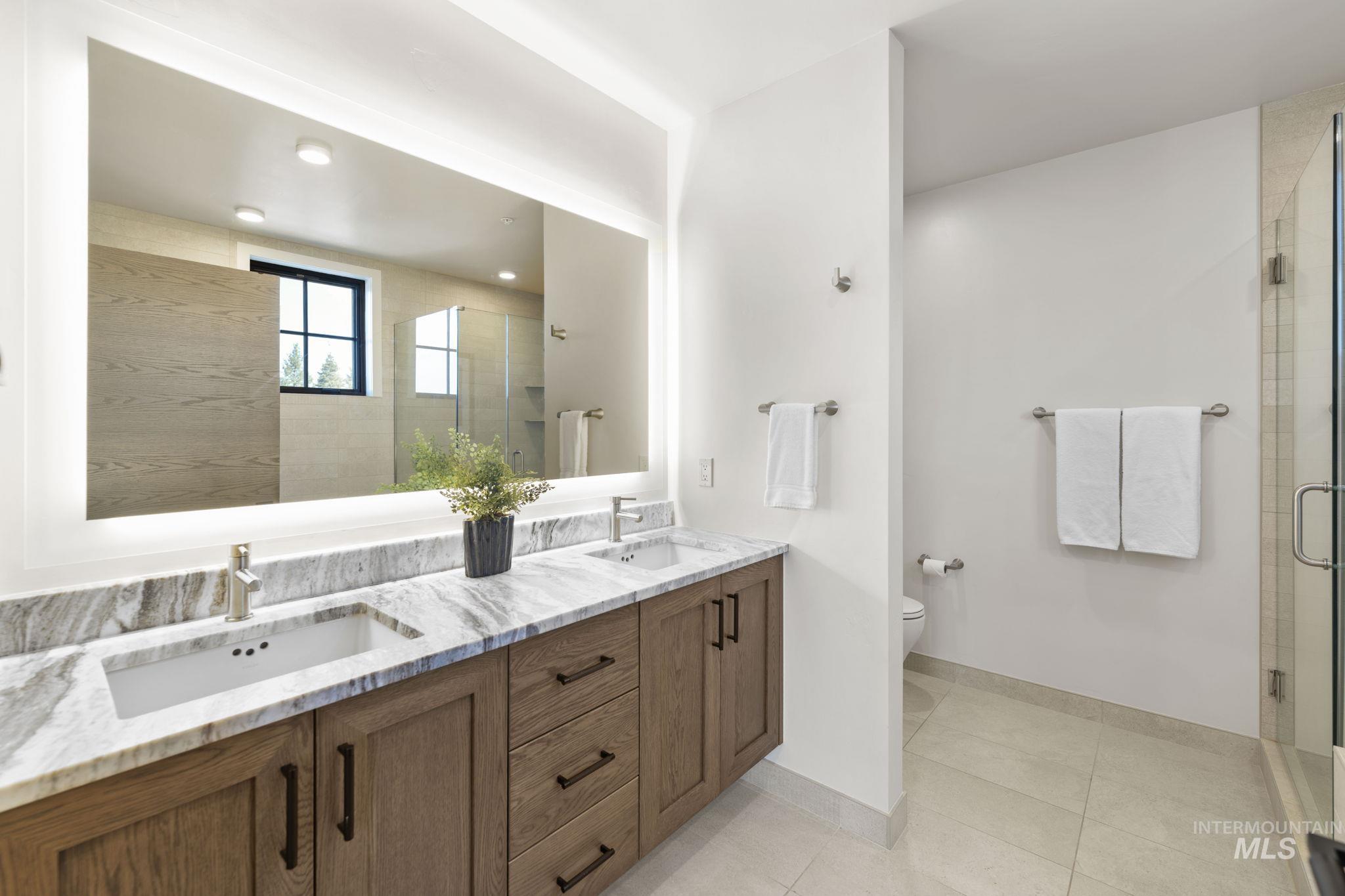 Full bathroom featuring double vanity, a shower stall, and light tile patterned floors