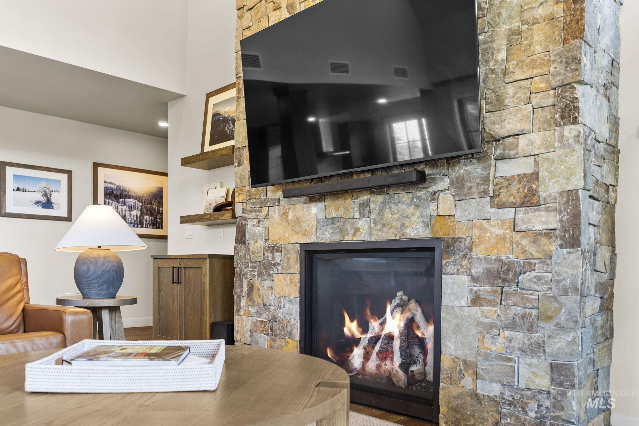 Living area featuring a stone fireplace and baseboards