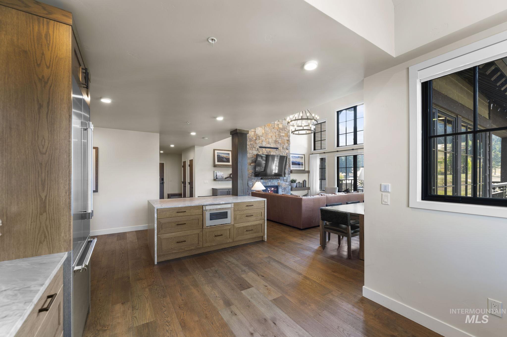 Kitchen with dark wood finished floors, open floor plan, recessed lighting, light stone counters, and white microwave