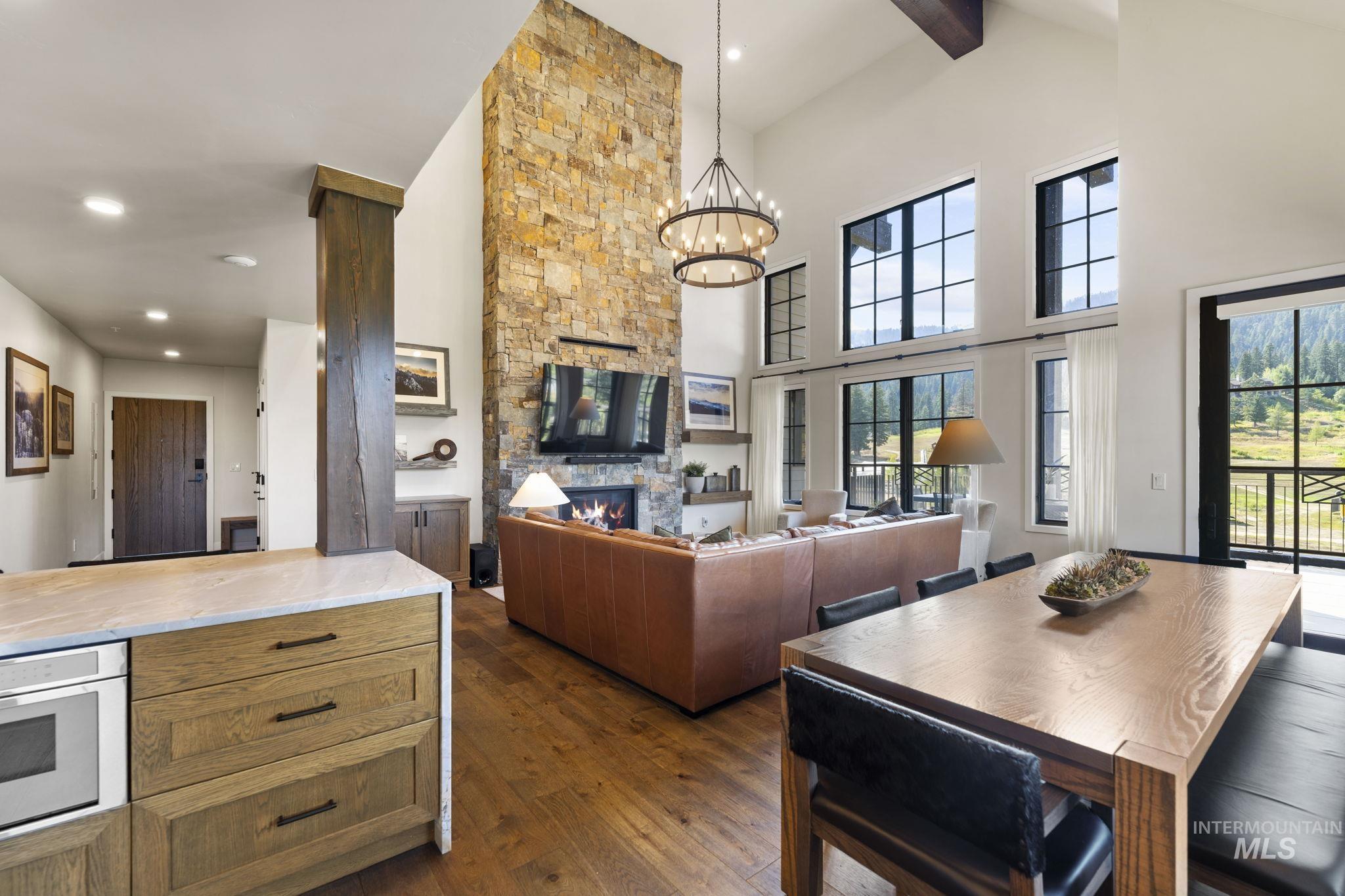 Dining space featuring a fireplace, dark wood finished floors, a chandelier, beamed ceiling, and recessed lighting