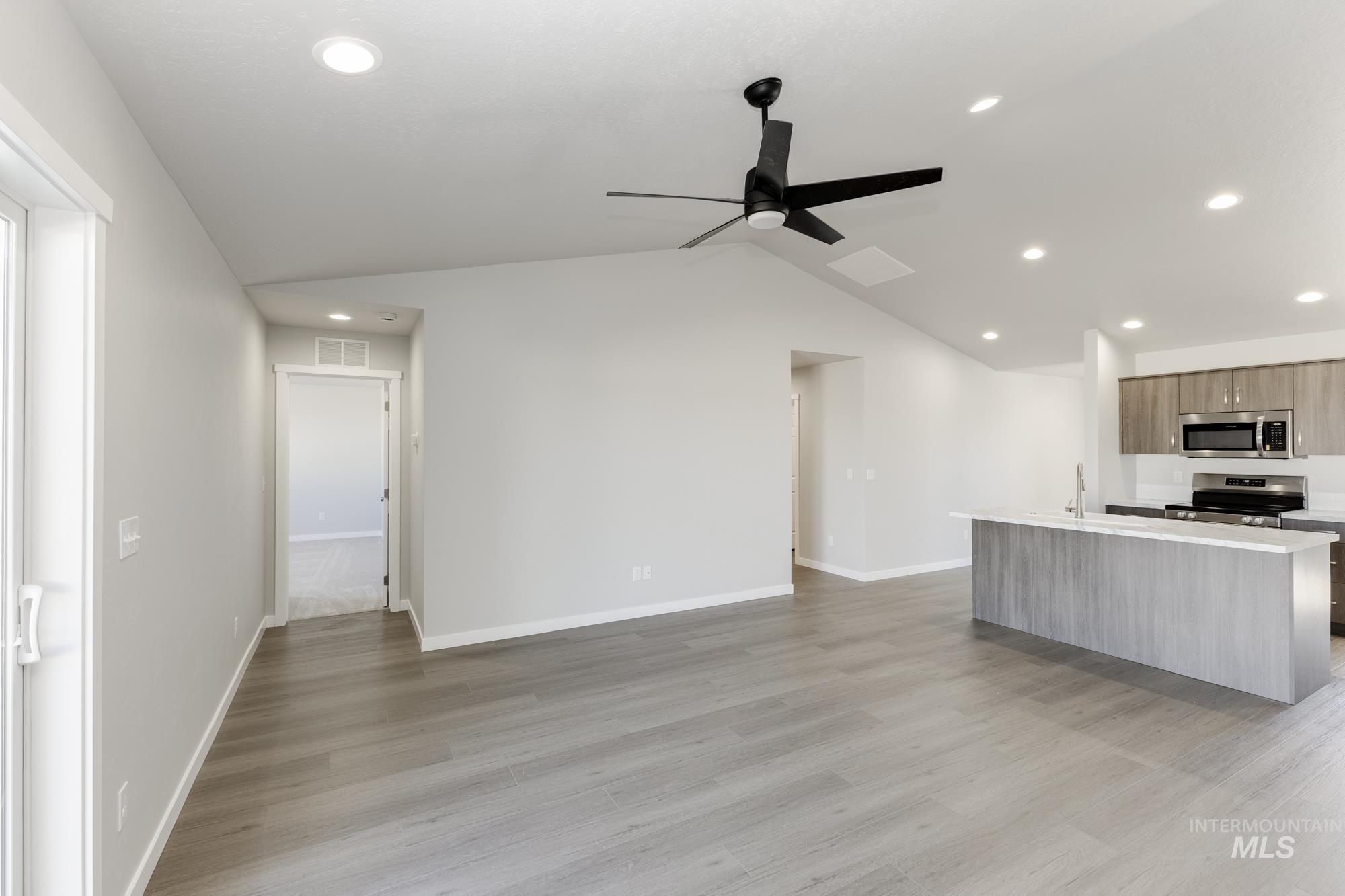 Kitchen with an island with sink, vaulted ceiling, recessed lighting, modern cabinets, and light wood finished floors