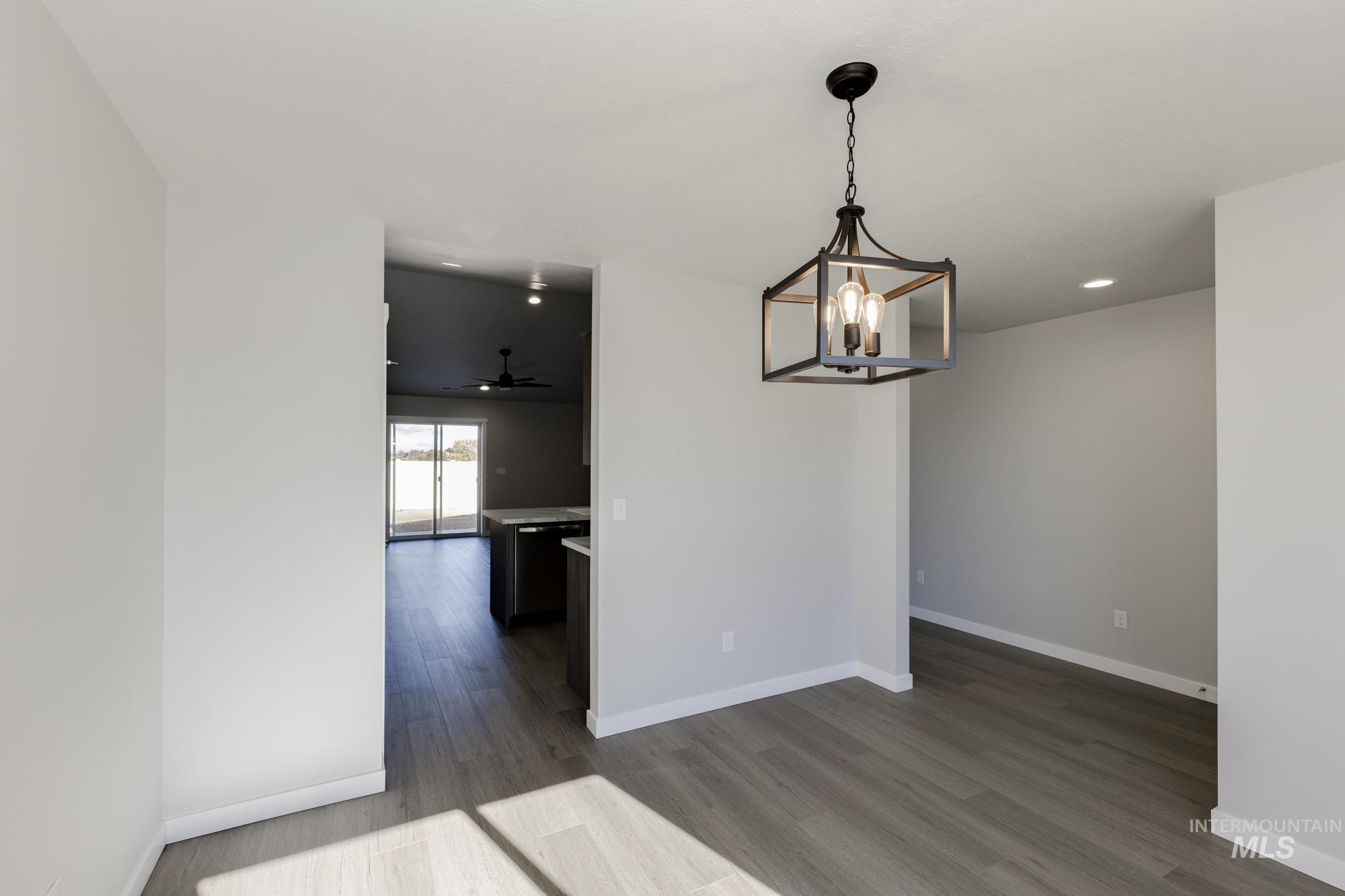 Unfurnished dining area with dark wood-type flooring, a chandelier, and ceiling fan