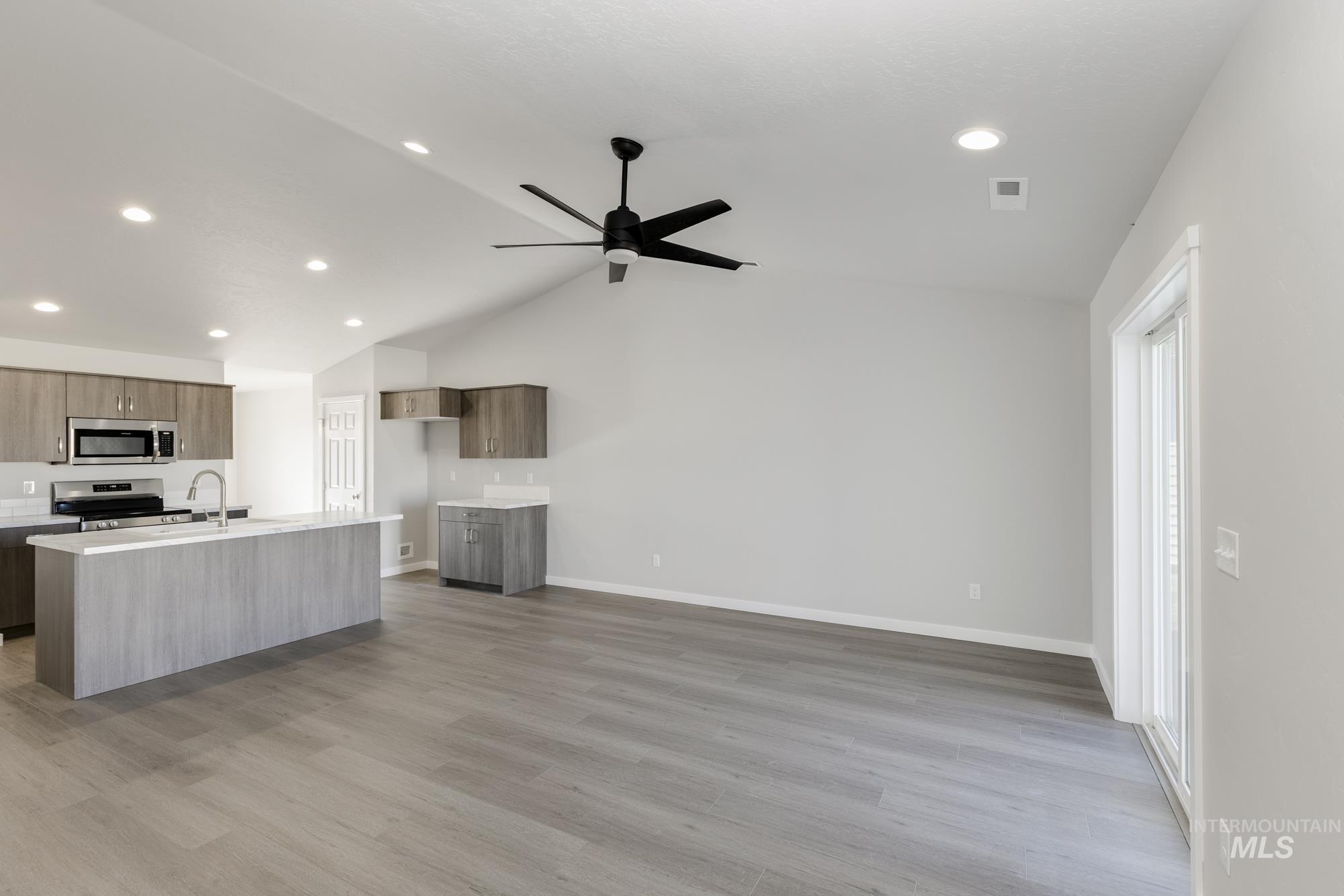 Kitchen featuring lofted ceiling, modern cabinets, light wood-type flooring, a center island with sink, and open floor plan