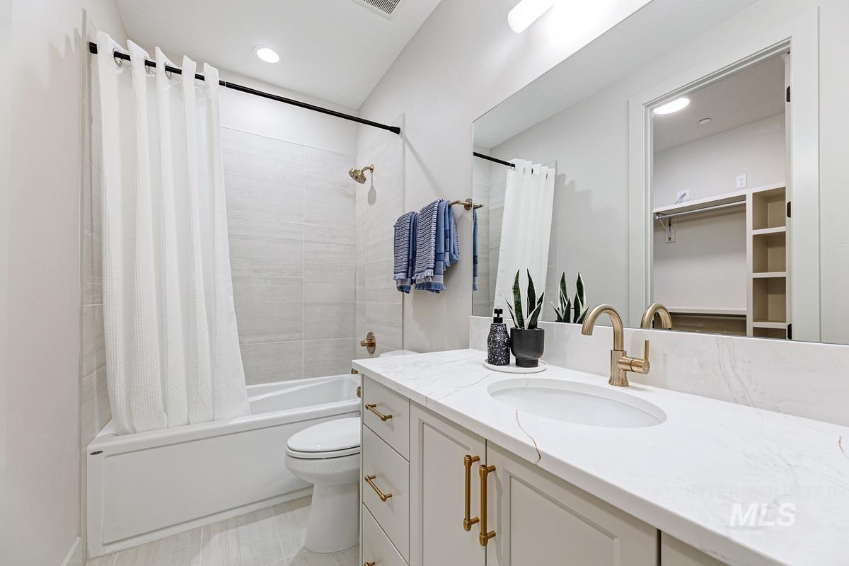 Bathroom with shower / bathtub combination with curtain, vanity, recessed lighting, and a spacious closet