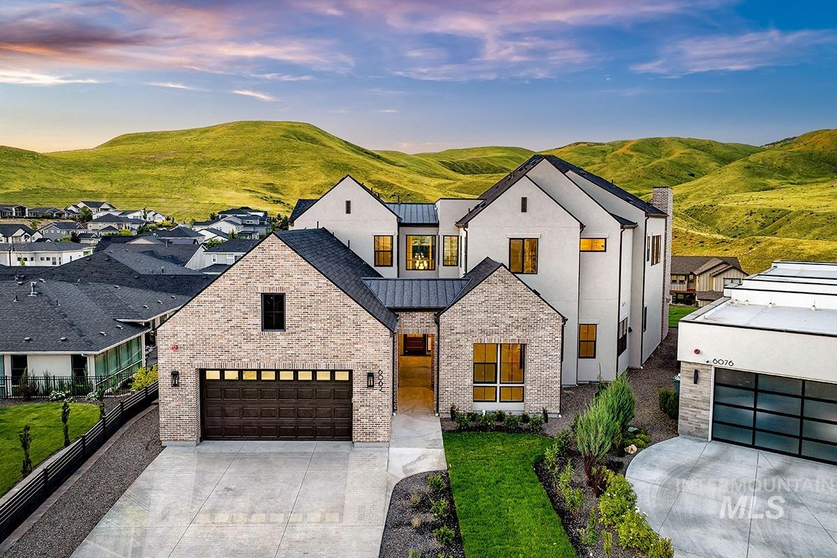 View of front of home featuring a standing seam roof, brick siding, a metal roof, concrete driveway, and a mountain view