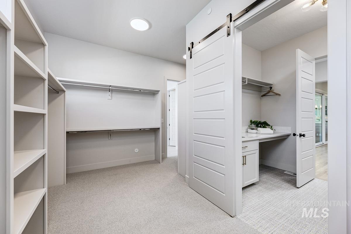Spacious closet with light colored carpet and a barn door