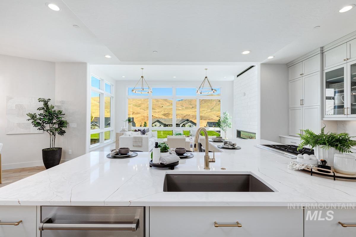 Kitchen with light stone countertops, recessed lighting, white cabinetry, a chandelier, and glass insert cabinets