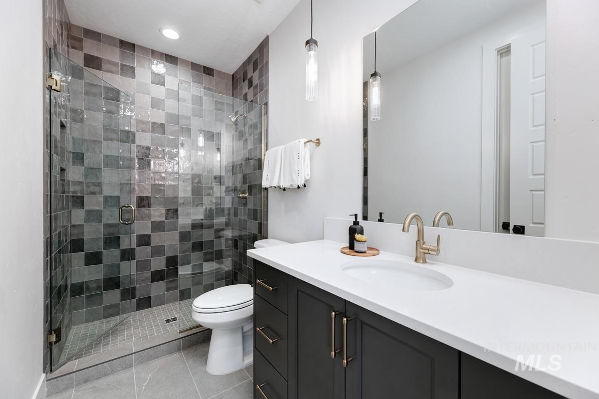 Full bath with a stall shower, vanity, and light tile patterned floors