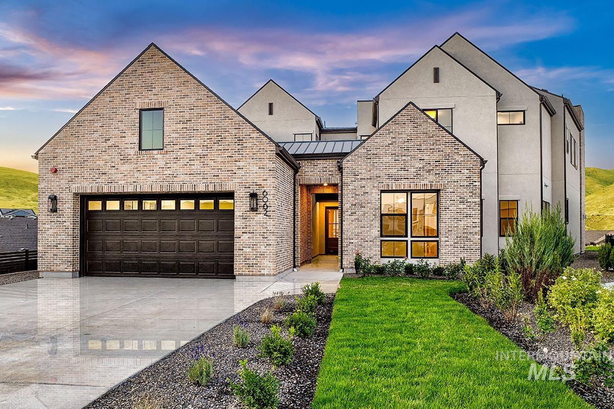 View of front of house with brick siding, a standing seam roof, driveway, a garage, and a front yard