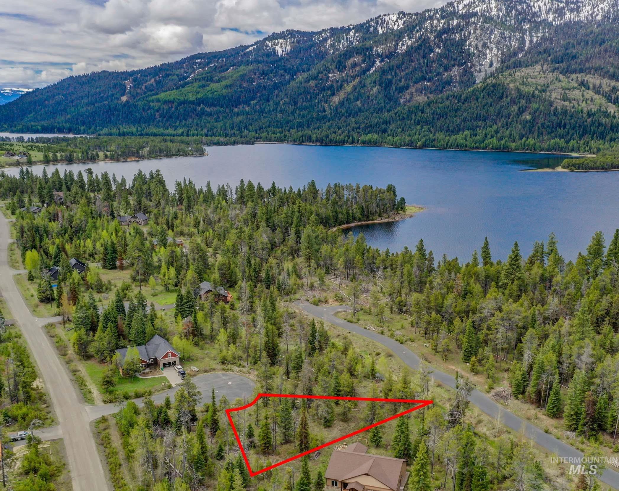 Aerial view of property and surrounding area featuring property parcel outlined and a water and mountain view