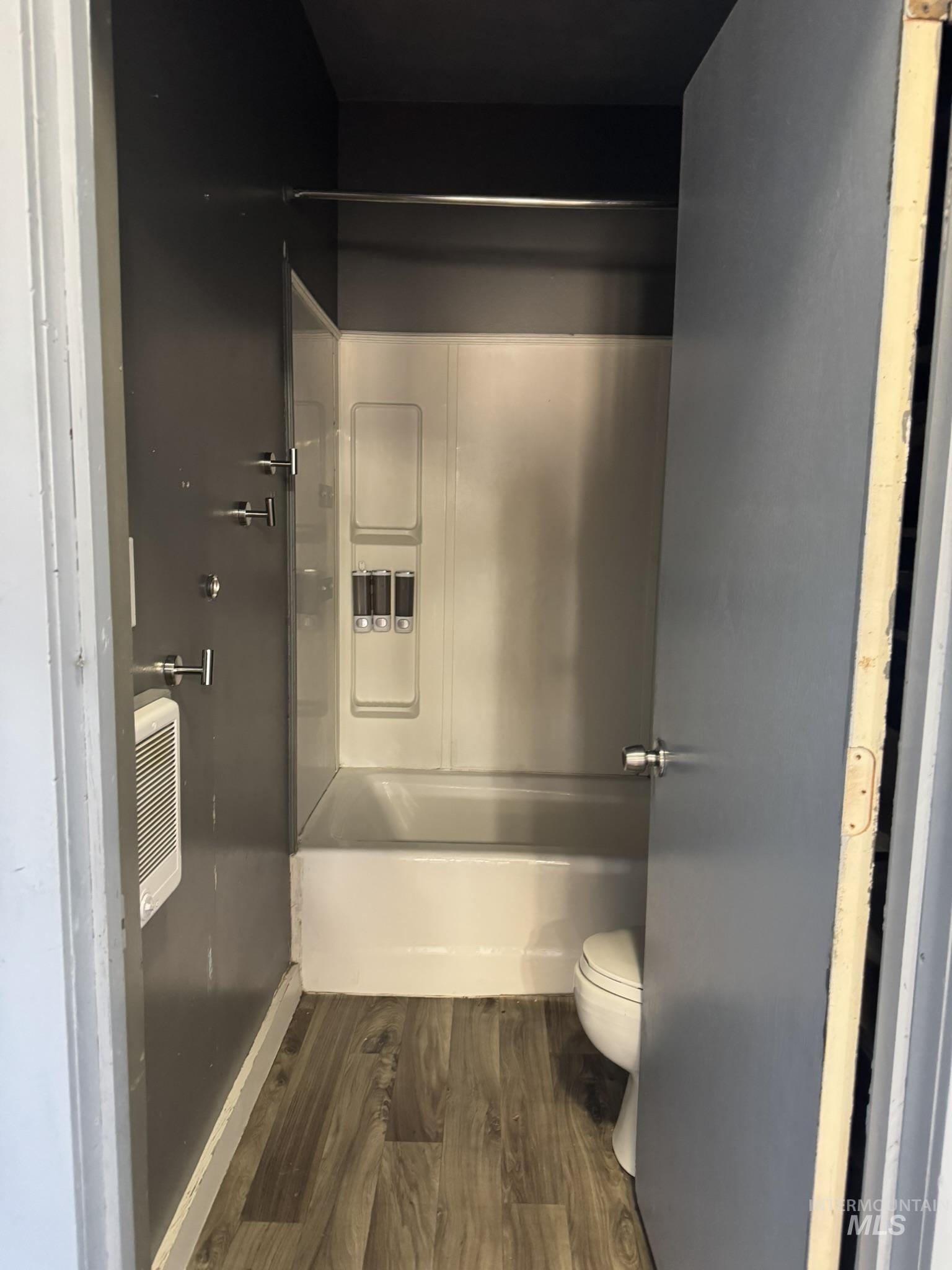 Full bathroom featuring dark wood finished floors and combined bath / shower with glass door
