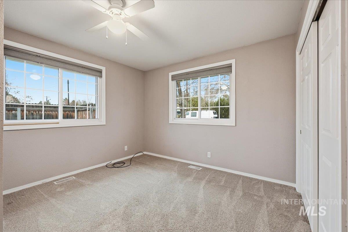 Unfurnished bedroom featuring light carpet, a closet, and multiple windows