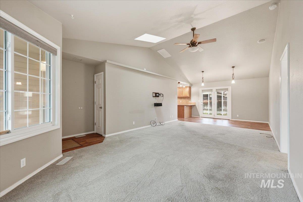 Unfurnished living room featuring vaulted ceiling, carpet floors, and ceiling fan