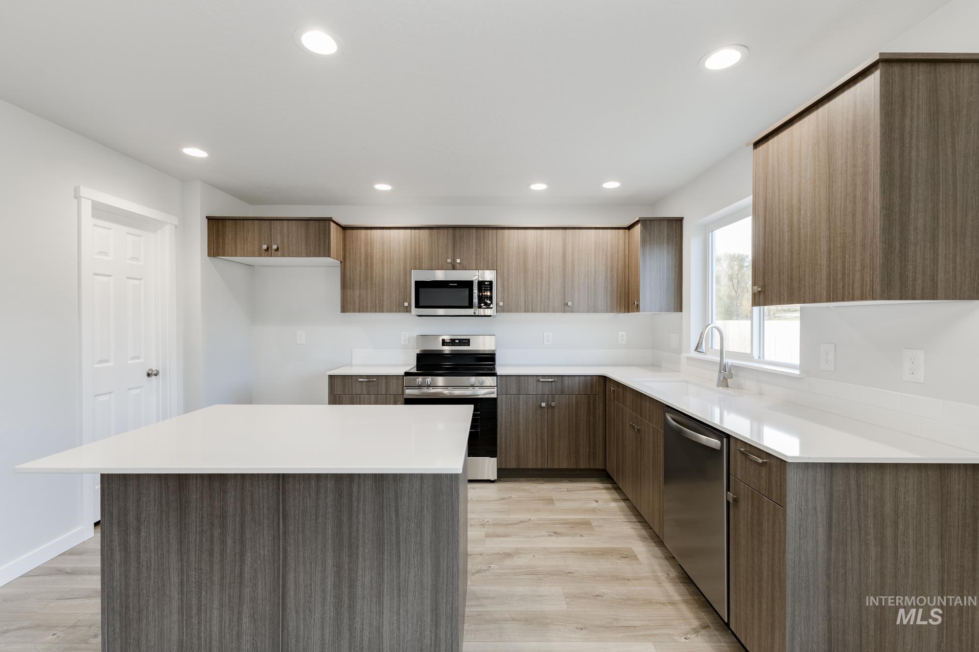 Kitchen featuring appliances with stainless steel finishes, a center island, modern cabinets, light wood-style flooring, and recessed lighting