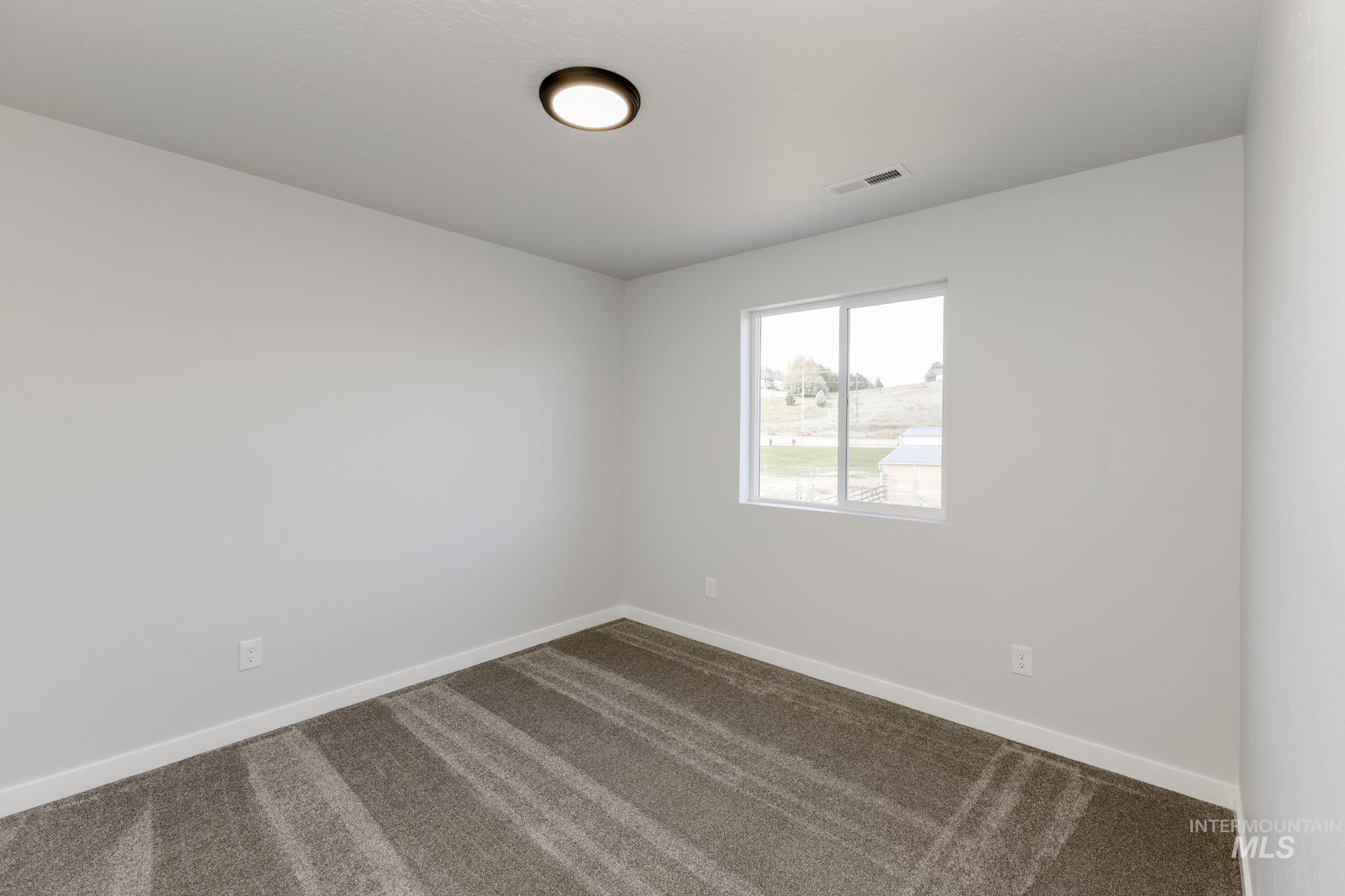 Unfurnished room with dark colored carpet and baseboards